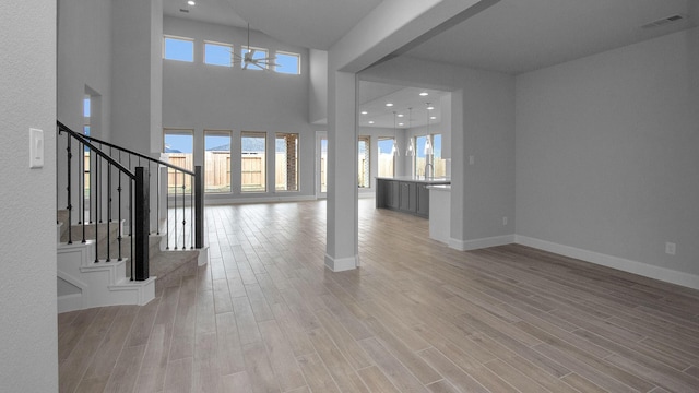 entrance foyer with light wood-style flooring, stairs, baseboards, and a wealth of natural light