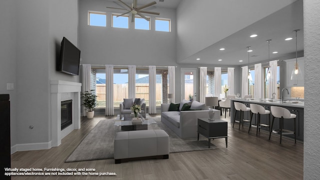 living area featuring ceiling fan, a glass covered fireplace, wood finished floors, and recessed lighting