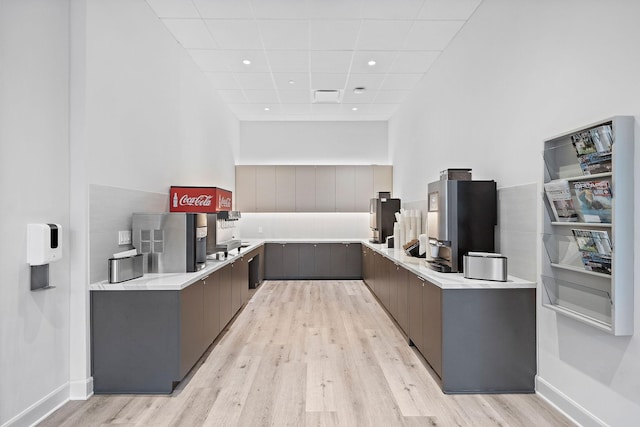 kitchen with a paneled ceiling, stainless steel refrigerator, and light hardwood / wood-style flooring