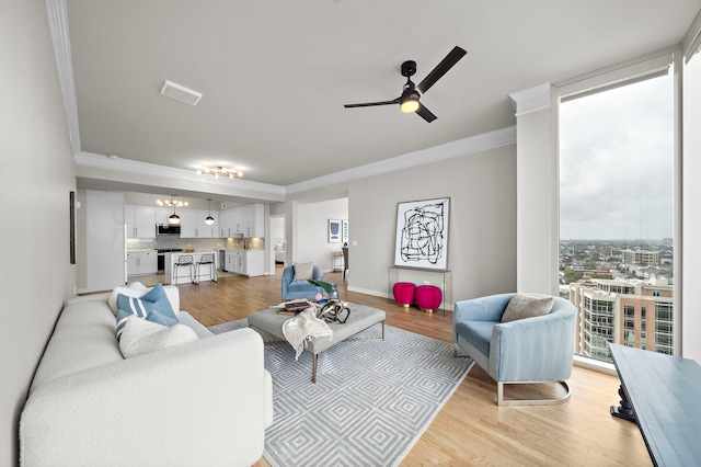 living room with ceiling fan, a healthy amount of sunlight, light wood-type flooring, and crown molding