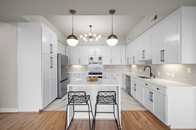 kitchen with white cabinetry, sink, a kitchen island, and stainless steel appliances