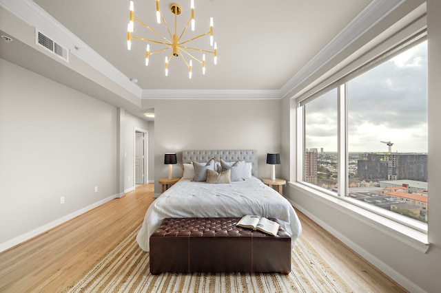 bedroom with light hardwood / wood-style floors, an inviting chandelier, and crown molding