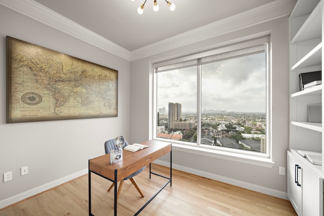 home office with light wood-type flooring, crown molding, a healthy amount of sunlight, and a notable chandelier