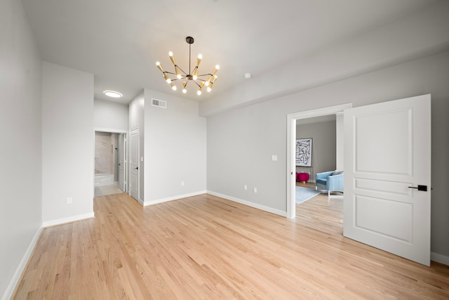 unfurnished room with a notable chandelier and light wood-type flooring