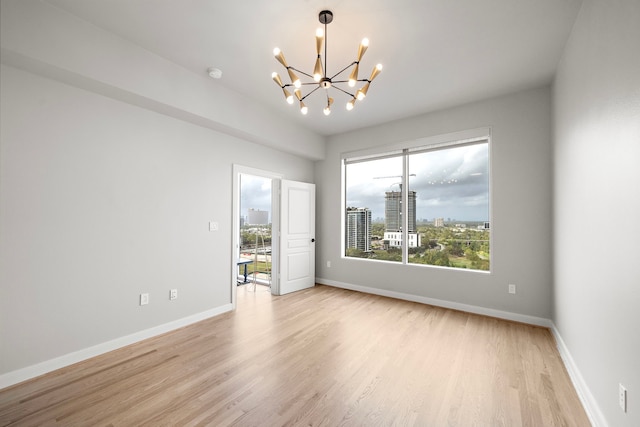 unfurnished room featuring an inviting chandelier and light hardwood / wood-style flooring