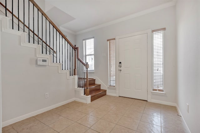 entrance foyer with ornamental molding, a healthy amount of sunlight, and light tile patterned floors