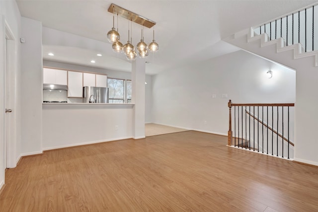 unfurnished living room with a chandelier and light wood-type flooring