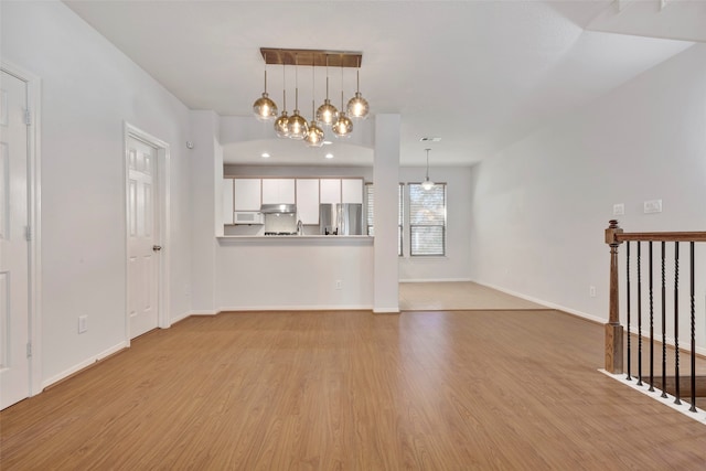 unfurnished living room with light hardwood / wood-style floors and a chandelier