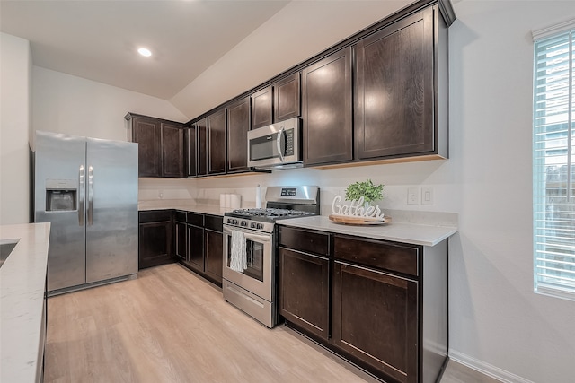 kitchen with lofted ceiling, appliances with stainless steel finishes, dark brown cabinetry, and light wood-type flooring