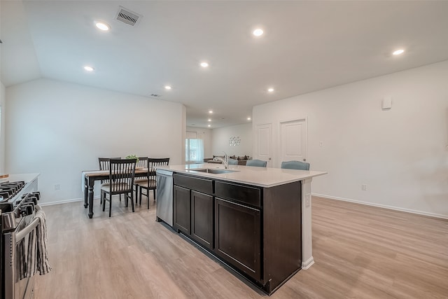 kitchen featuring lofted ceiling, appliances with stainless steel finishes, a kitchen island with sink, light hardwood / wood-style flooring, and sink