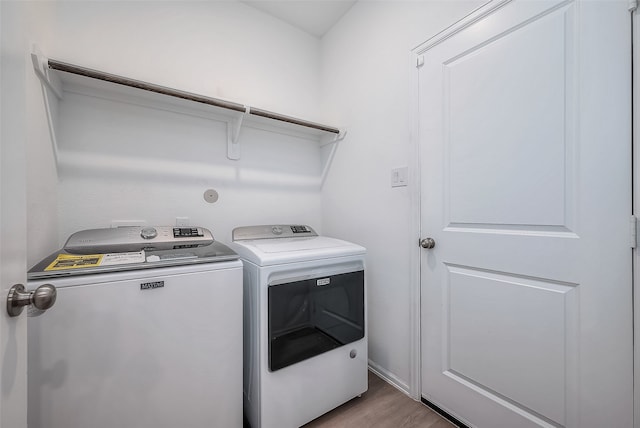 clothes washing area with light hardwood / wood-style floors and washing machine and clothes dryer