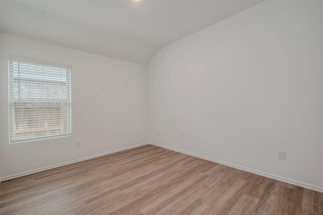 unfurnished room with lofted ceiling and light wood-type flooring