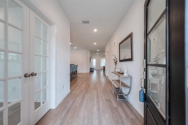 hallway with french doors and light hardwood / wood-style flooring