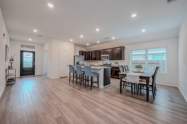 kitchen with appliances with stainless steel finishes, a healthy amount of sunlight, a center island with sink, and light hardwood / wood-style floors