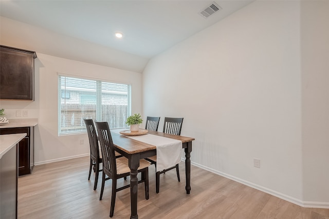 dining area with vaulted ceiling and light wood-type flooring