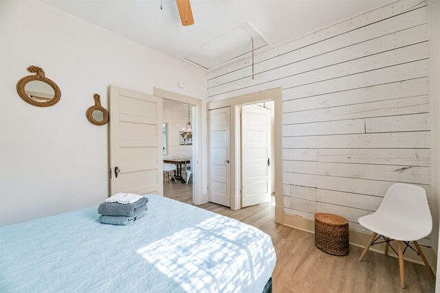 bedroom featuring hardwood / wood-style floors, ceiling fan, and wood walls