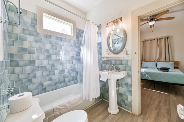 bathroom with toilet, shower / bath combo with shower curtain, wood-type flooring, and tile walls