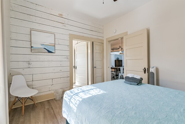 bedroom with hardwood / wood-style floors and wood walls