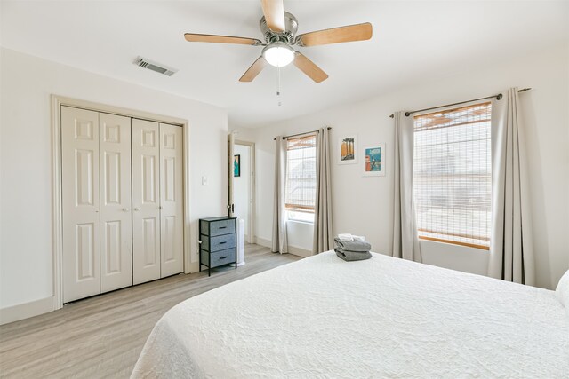 bedroom with a closet, light hardwood / wood-style floors, multiple windows, and ceiling fan