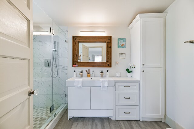 bathroom with a shower with door, vanity, and hardwood / wood-style flooring