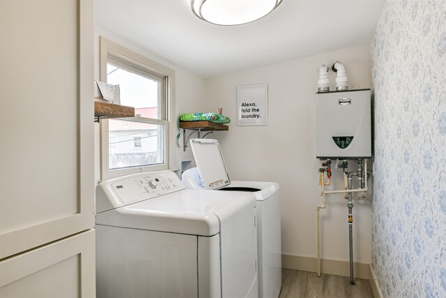 laundry area with light hardwood / wood-style flooring, independent washer and dryer, and tankless water heater