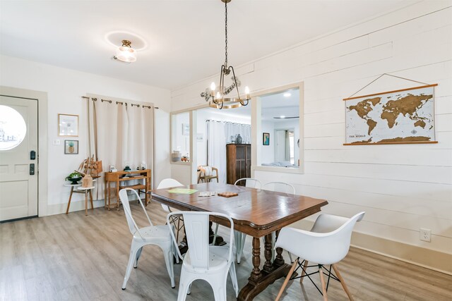 dining space featuring wooden walls, a notable chandelier, and wood-type flooring