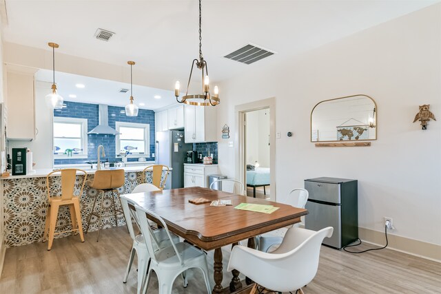 dining area featuring sink, a chandelier, and light hardwood / wood-style floors