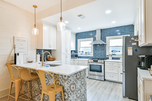 kitchen featuring light hardwood / wood-style flooring, wall chimney range hood, stainless steel appliances, and white cabinets