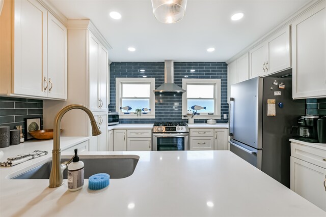 kitchen featuring wall chimney exhaust hood, sink, stainless steel appliances, and backsplash