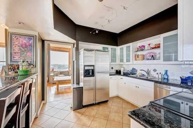 kitchen with stainless steel appliances, a textured ceiling, and white cabinets