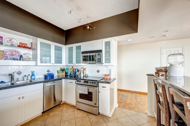 kitchen with stainless steel appliances, decorative backsplash, light tile patterned floors, and white cabinets