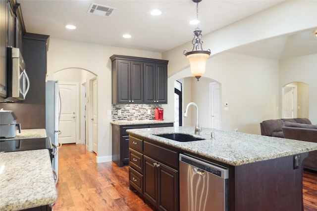 kitchen featuring appliances with stainless steel finishes, dark hardwood / wood-style flooring, a center island with sink, and sink