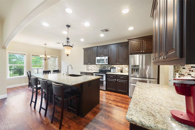 kitchen featuring sink, hanging light fixtures, dark wood-type flooring, an island with sink, and appliances with stainless steel finishes