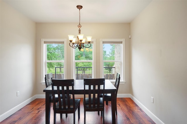 dining room with a wealth of natural light, dark wood-type flooring, and a notable chandelier