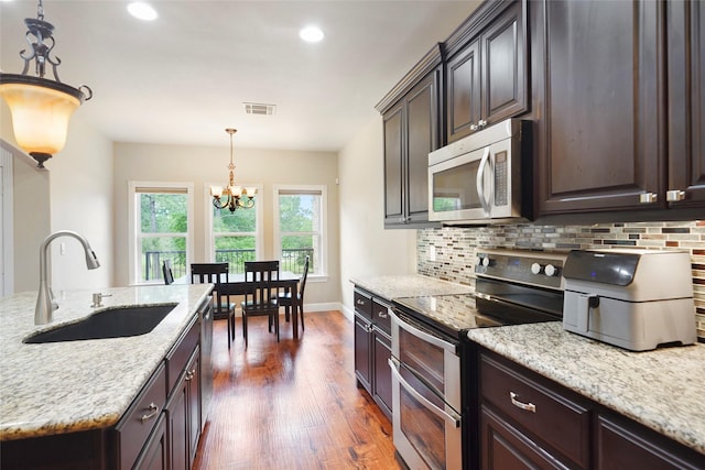 kitchen featuring dark brown cabinetry, stainless steel appliances, dark wood-type flooring, sink, and a notable chandelier