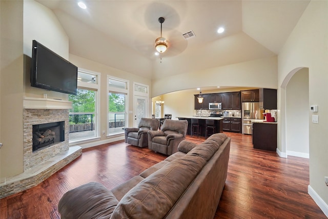 living room featuring ceiling fan, dark hardwood / wood-style flooring, a fireplace, and high vaulted ceiling