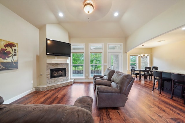 living room with a fireplace, dark hardwood / wood-style flooring, ceiling fan with notable chandelier, and vaulted ceiling