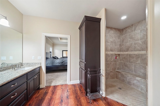 bathroom featuring a tile shower, hardwood / wood-style floors, and vanity