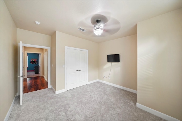 unfurnished bedroom featuring ceiling fan, a closet, and light carpet