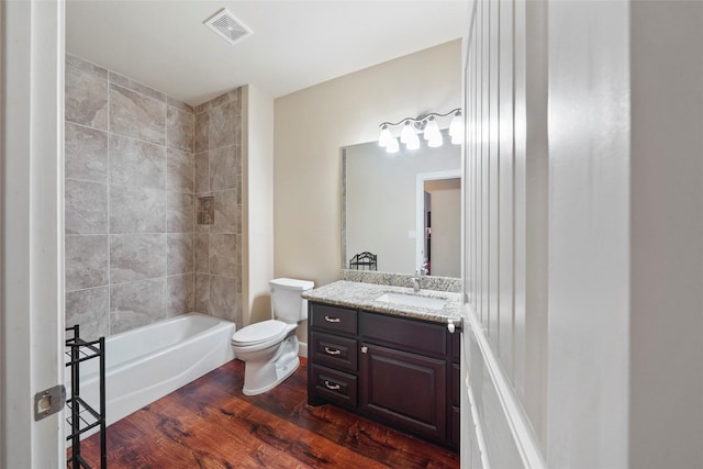 full bathroom with hardwood / wood-style floors, vanity, toilet, and tiled shower / bath combo