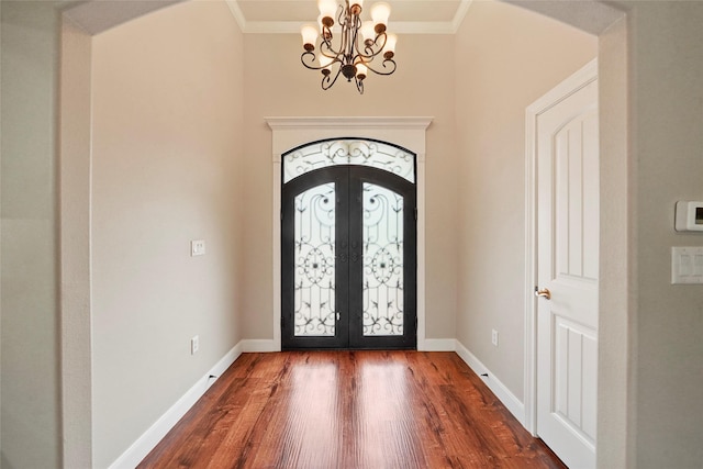 foyer entrance with dark hardwood / wood-style floors, ornamental molding, and french doors