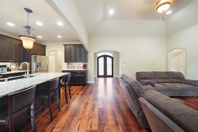 kitchen featuring stainless steel refrigerator with ice dispenser, dark brown cabinetry, dark hardwood / wood-style flooring, and sink