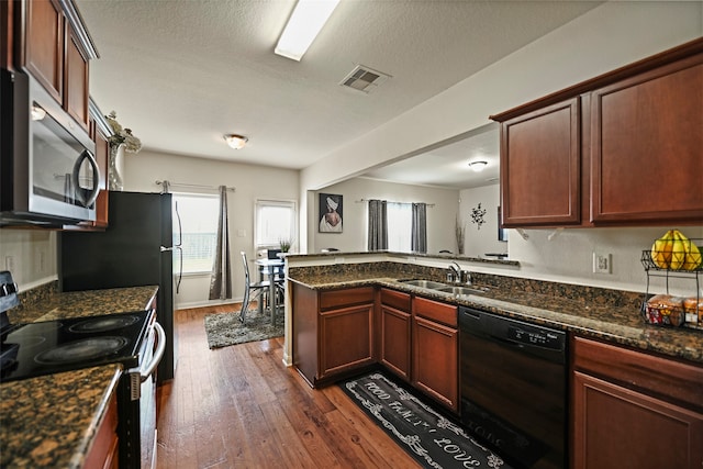 kitchen featuring dark stone countertops, dark wood-type flooring, black appliances, and sink