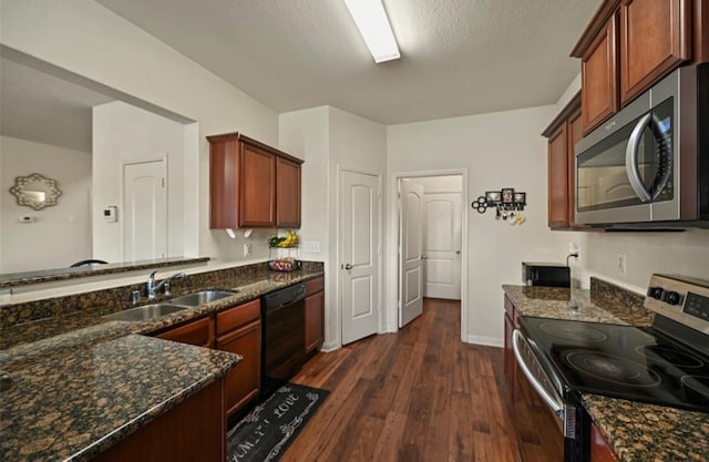 kitchen with dark stone counters, stainless steel appliances, dark wood-type flooring, and sink