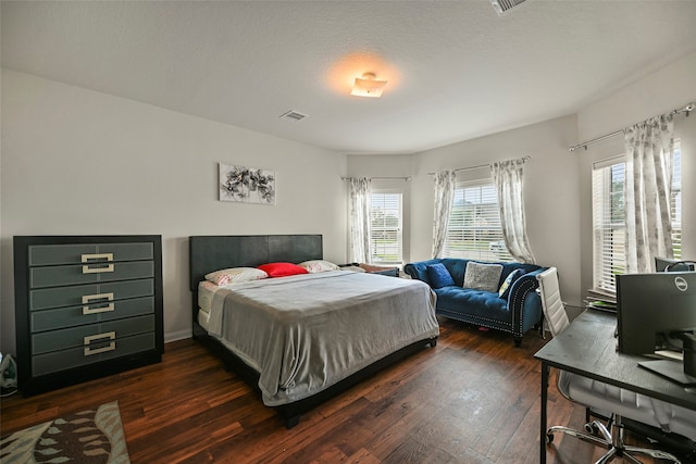 bedroom featuring a textured ceiling, dark hardwood / wood-style floors, and multiple windows