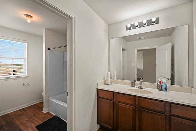 full bathroom featuring hardwood / wood-style floors, vanity, shower / washtub combination, toilet, and a textured ceiling