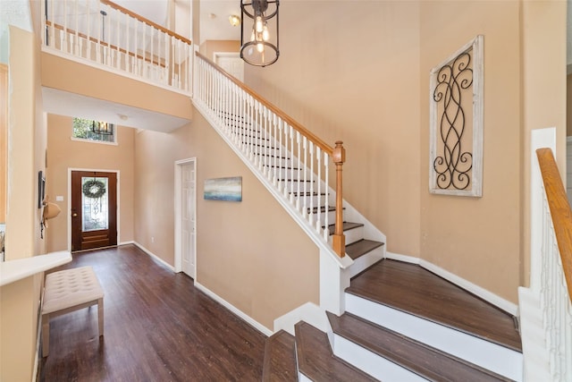 entrance foyer with a chandelier, dark hardwood / wood-style flooring, and a towering ceiling