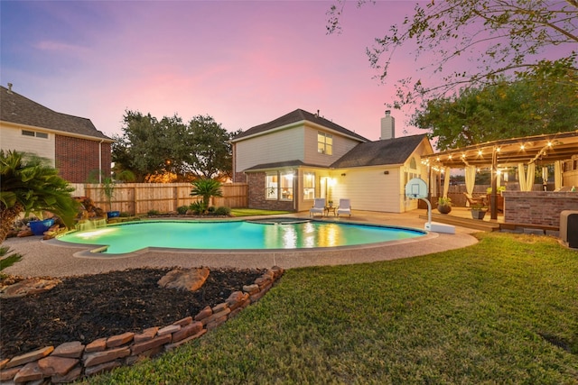 pool at dusk featuring a lawn, a hot tub, and a deck