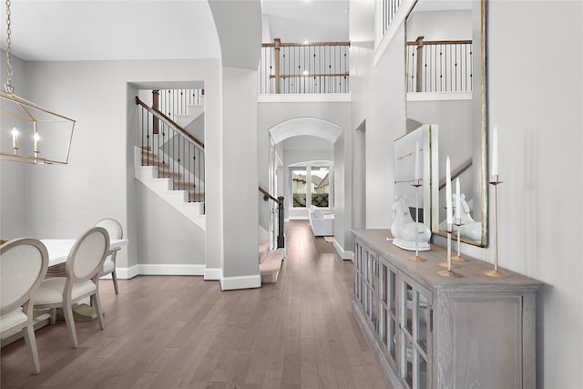 entrance foyer featuring a towering ceiling, wood-type flooring, and an inviting chandelier