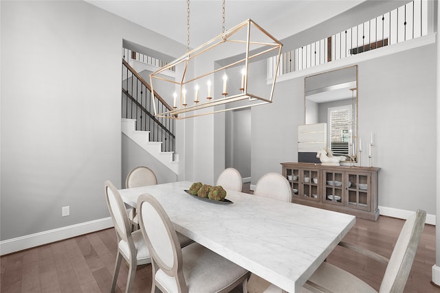 dining area featuring dark wood-type flooring, a chandelier, and a high ceiling